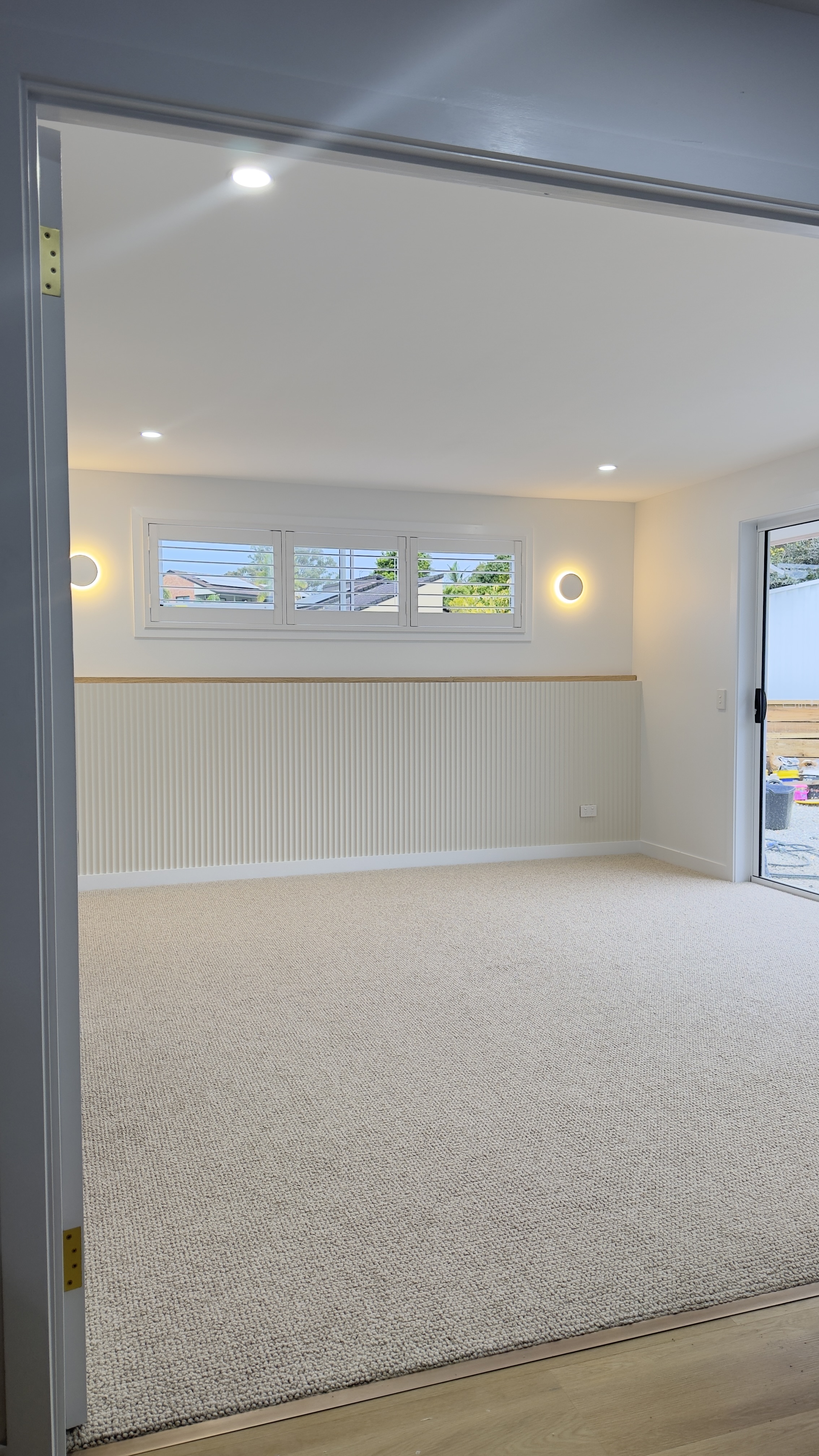Bedroom with half-height fluted panelling, timber trim cap and wall sconces