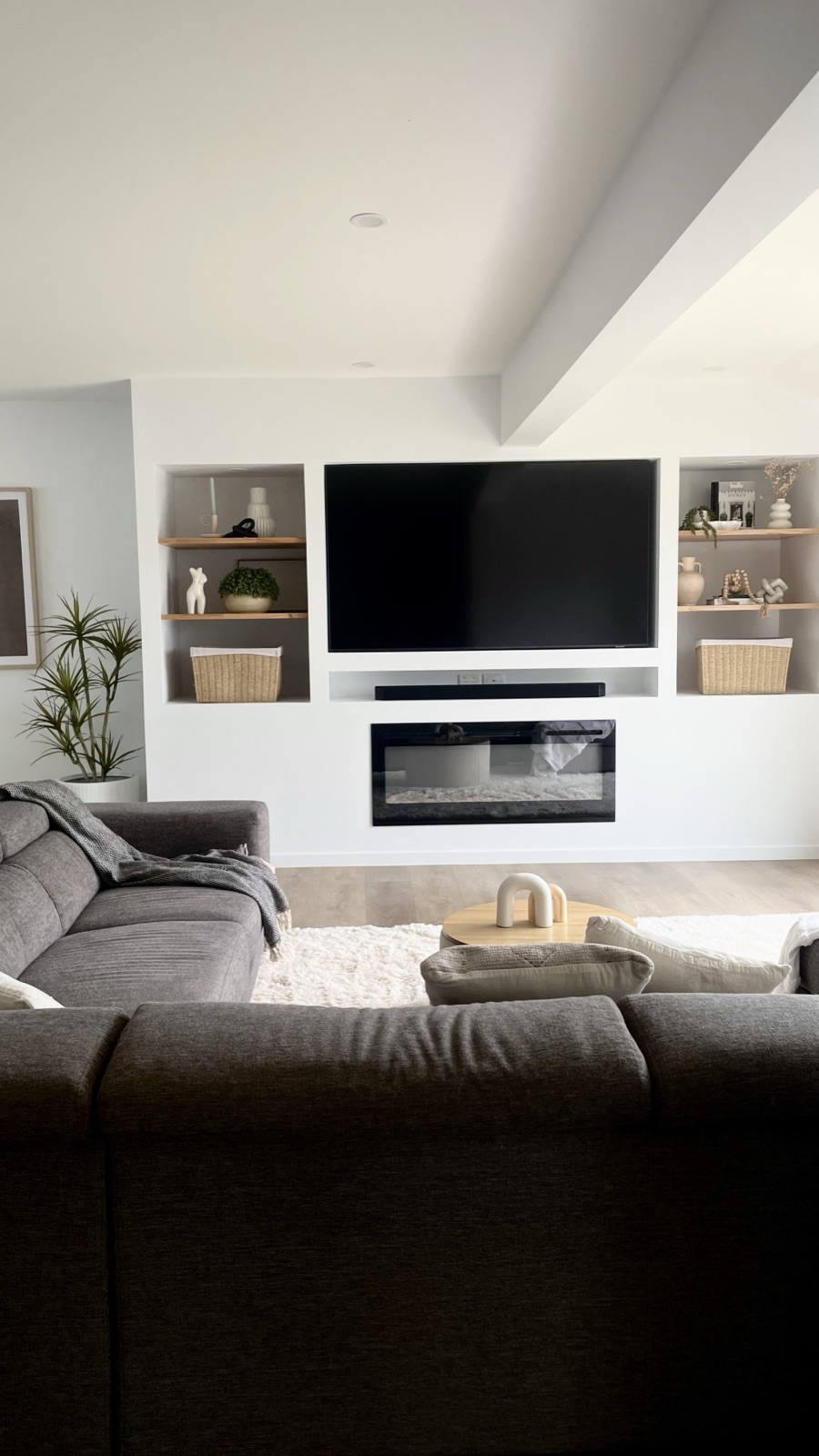 Custom media feature wall with integrated fireplace and timber shelving